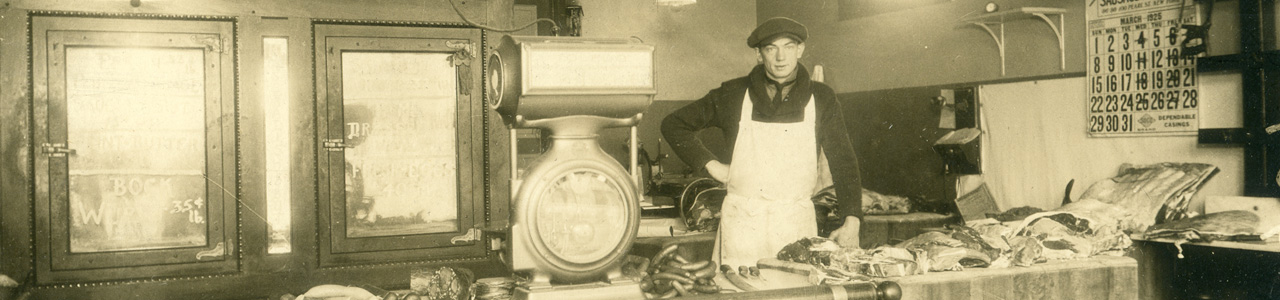 Old photo of man standing behind a meat counter