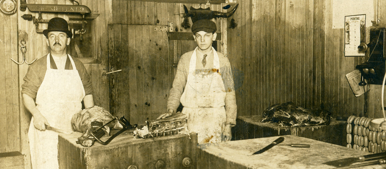 Old photo of two young men behind the counter in a meat shop